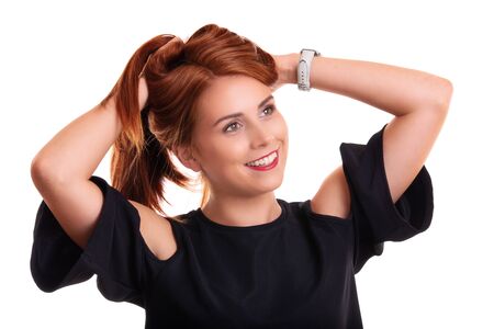 Portrait of a beautiful smiling young redhead woman with hands in her hair, isolated on white background.の写真素材