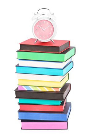 An alarm clock on top of stack of colorful books with different sprayed edges, isolated on white background. Education and time concept.の写真素材
