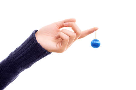 Female hand holding a Christmas ball ornament isolated on a white background. Blue round Christmas ornament in a womanâs hand. Christmas and New Year concept.の写真素材