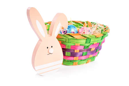 Close up of Easter bunny and a basket filled with colourful Easter eggs with polka dots, isolated on white background. Fun and colorful Easter celebration concept.の写真素材