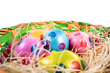 Close up of colourful Easter eggs with polka dots in a basket, isolated on white background. Easter celebration concept.の写真素材