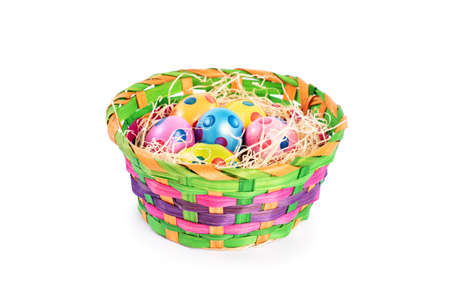 Colourful Easter eggs with polka dots in a basket, isolated on white background. Easter celebration concept.の写真素材