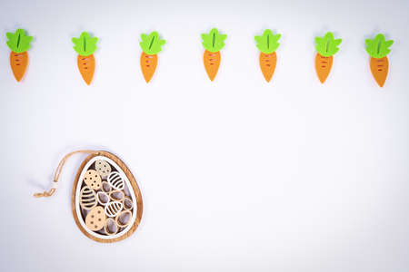 Easter pattern made with carrots and a cute Easter egg decoration on white background. Creative minimal holiday flat lay concept. Spring holidays concept. Top view. Copy space.の写真素材