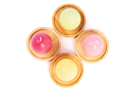 Top view of egg shaped candles in pastel colors on wooden saucers, isolated on white background. Fun and colorful Easter celebration concept. Easter decoration concept.の写真素材