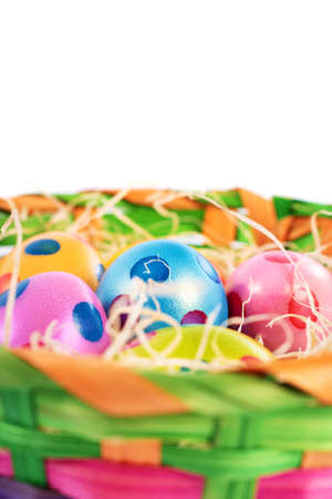 Close up of colourful Easter eggs with polka dots in a basket, isolated on white background. Easter celebration concept.の写真素材