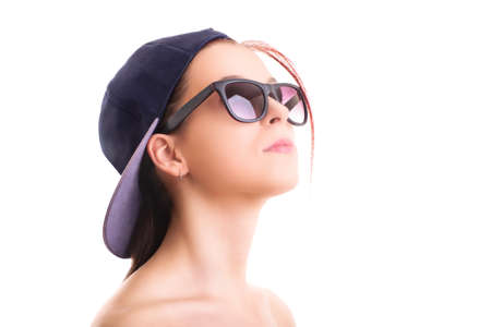 Close up shot of a beautiful stylish girl with backwards snapback cap and sunglasses, isolated on white background. Cool concept.の写真素材