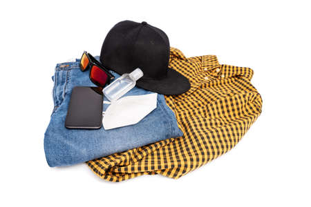 Modern stylish male outfit for the pandemic with jeans, plaid shirt, snapback cap, sunglasses, mobile phone, hand sanitizer and face mask, isolated on white background.の写真素材