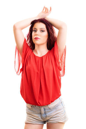 Beautiful redhead woman with long wavy hair in a fashionable summer outfit looking sensually to the camera, isolated on white background. Summer, enjoying concept.の写真素材