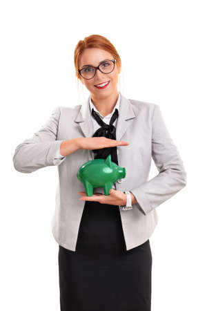 Beautiful smiling businesswoman holding a green piggy bank, isolated on white background. Finance, banking, loan, savings concept.の写真素材