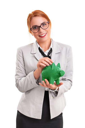 Young smiling businesswoman inserting a coin in piggy bank, isolated on white background. Finance, savings concept.の写真素材