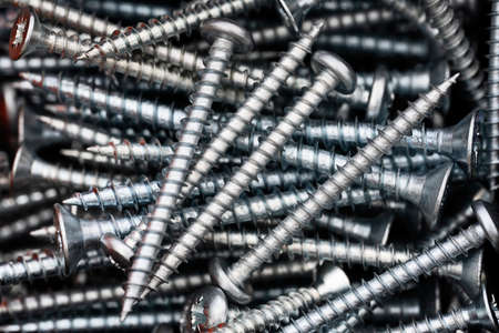Close up of a pile of multipurpose metal screws. Industrial and construction concept. Metal screw, iron screw, chrome screw.の写真素材