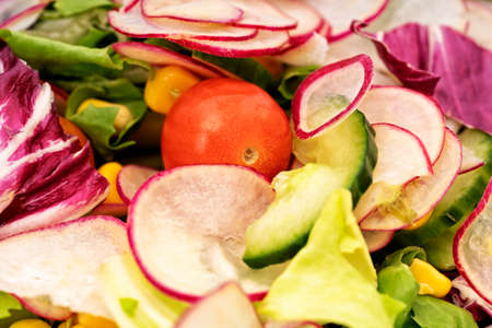 Close up of fresh healthy salad with cherry tomatoes, cucumber, radishes, and mixed greens. Healthy food concept.の写真素材