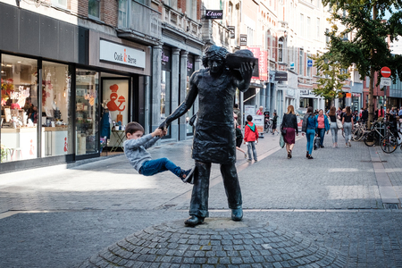 Leuven, Belgium - October 14th, 2017: Young boy hanging on a statue in the city of Leuvenのeditorial素材