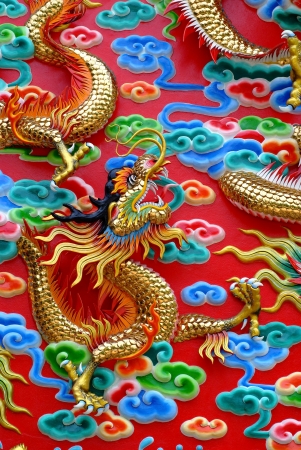 The carvings of the golden dragon are displayed outside the walls of Kratuemsueapla Temple in Bangkok, Thailand  The carvings depict a Chinese myth where the dragon used to be a koi, and was transformed into a dragon when it succeeded in leaping over the の写真素材
