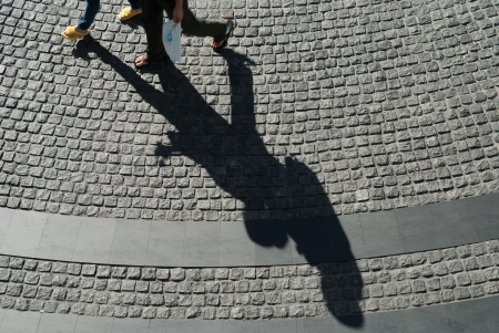 Two person with shadow on the black cobblestoneの写真素材