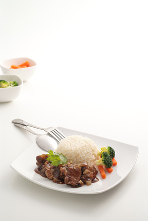 Fried pork ribs pour sauce with rice on white backgroundの写真素材