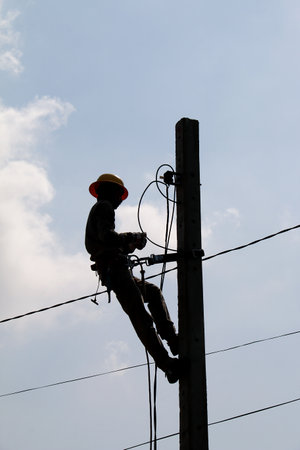 Silhouette image of electrician is working on the electric pole