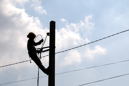 Silhouette image of electrician is working on the electric poleの写真素材