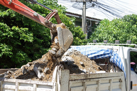 A backhoe is dumping the excavated land onto a truck
