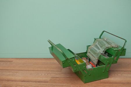 Green metal tool box with sliding sections. It is laid out, on top is a set of wrenches.