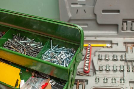 Green metal tool box. Compartment for self-tapping screws. Against the background of a case with...