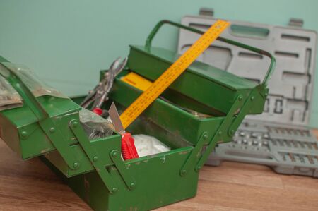 Green metal toolbox on a wooden floor with a green background. Closeup photo with copyspace.の写真素材