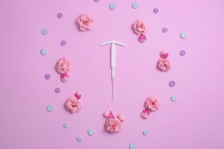 Concept hormonal contraception - pills, IUD, beautiful shiny tablets on a pink background, with paper flowers.の写真素材
