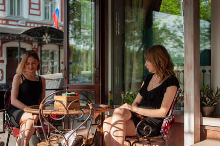 Russia, Ulyanovsk, May 11, 2019. Two woman friends sit in a cafe and wait for an order.のeditorial素材