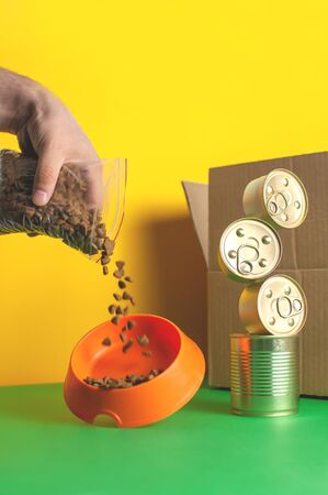 Concept delivery of pet food. Mens hand pours dry food into a bowlの写真素材