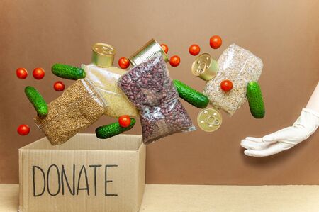Food donation box. Hand in glove receiving food assistance. Safe food deliveryの写真素材