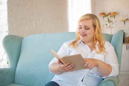 Young overweight woman reads paper book, rest alone, self-developmentの写真素材