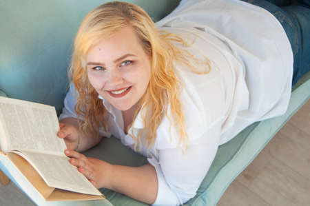 Young overweight woman reads paper book, rest alone, self-developmentの写真素材