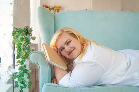 Young overweight woman reads paper book, rest alone, self-development