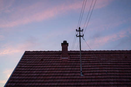 Blue evening sky with pink clouds over the roof of the houseの写真素材