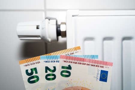 Euro money in front of a white radiator because gas is becoming more expensiveの写真素材