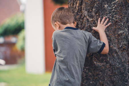 Little boy is walking around a tree in the park