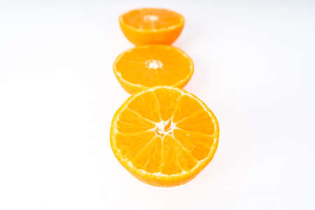 Three half tangerines in a row on a white backgroundの写真素材