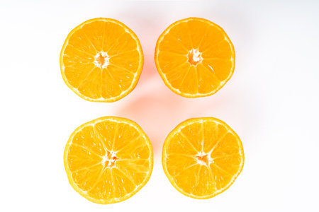 Four half orange colored tangerines in the middle of a white backgroundの写真素材