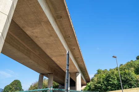 Bottom view of a large modern concrete bridge on which vehicles are driving