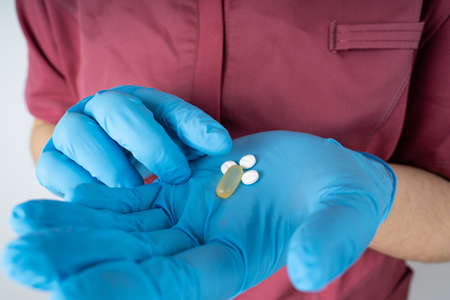 Nurse with medical uniform and blue medicine gloves holds medicines in her handの写真素材