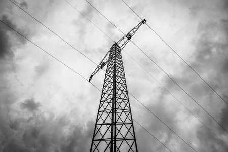 Bottom up view of an electricity pylon with high voltage power lines in black and whiteの写真素材