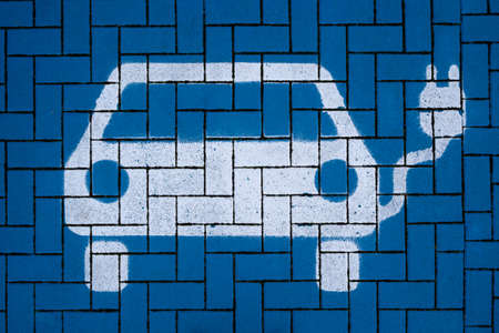 White electric vehicle symbol on blue paving stones in a charging stationの写真素材