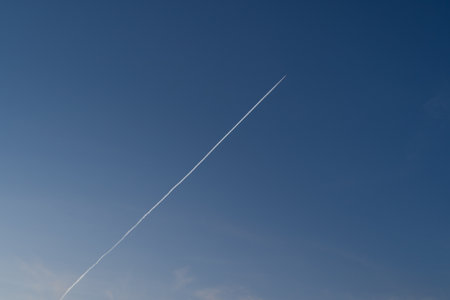 Flying airplane with contrails in the blue sky