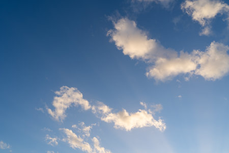 Blue sunny sky with white clouds on a spring eveningの写真素材