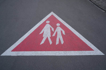 Triangular warning sign on the paved road showing walking pedestrians. Drivers drive carefully and watch out for pedestrians.の写真素材