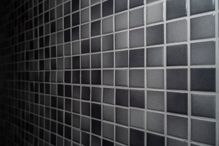 Bathroom wall made of small light gray and dark gray mosaic tiles and silver gray groutの写真素材