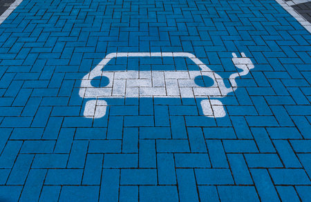 White electric vehicle symbol on blue floor of a charging stationの写真素材