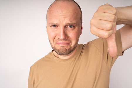 Young man making sad face and showing thumb down