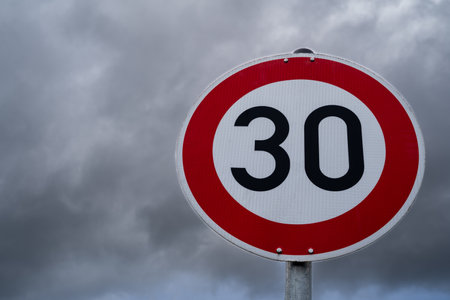 Round speed sign 30 kilometers per hour with cloudy sky in the backgroundの写真素材