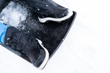 Children's feet with boots on a sled in the snow